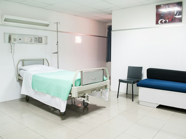 Hospital bed set up beside a sofa in a bright room