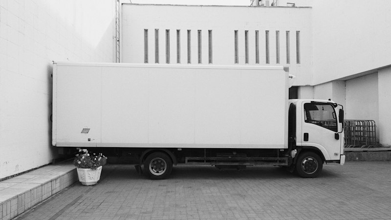 White delivery truck parked beside a white building