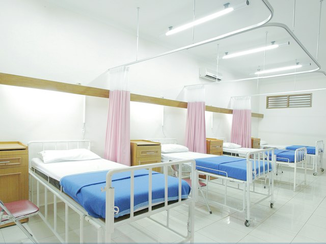 Empty hospital ward bed in a bright room