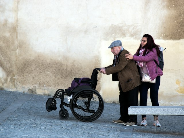 Carer helping an older man in a wheelchair