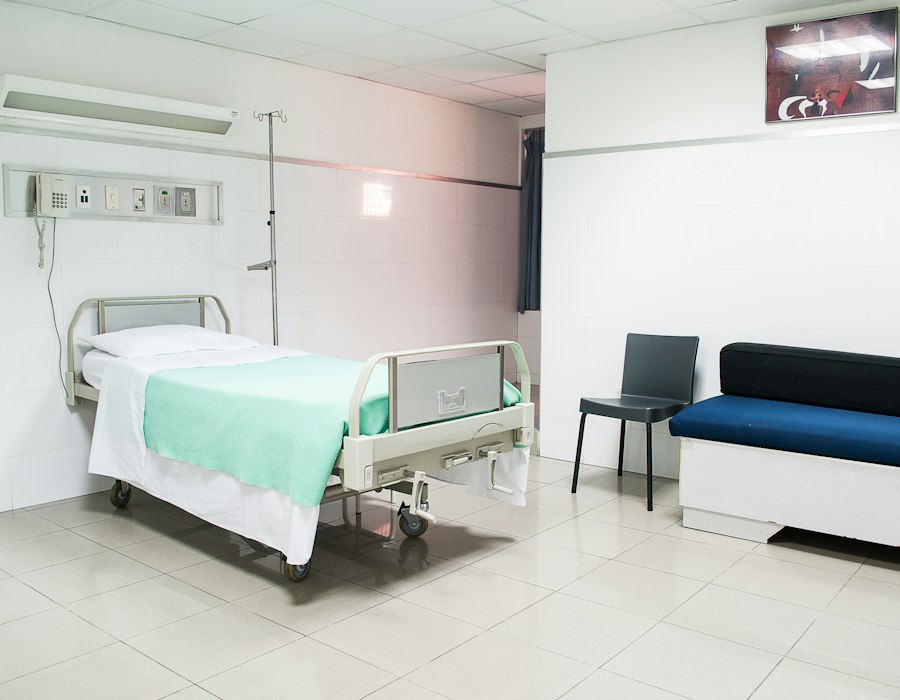 Hospital bed set up beside a sofa in a bright room